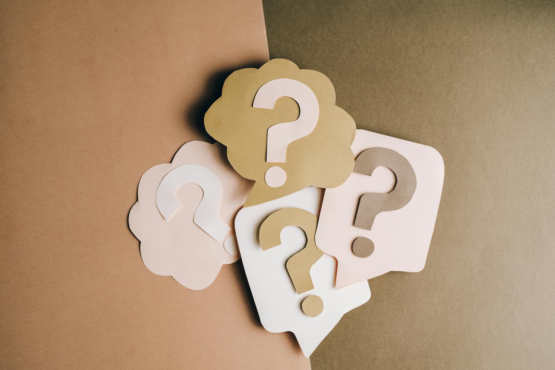 Paper cutouts of question marks in neutral tones