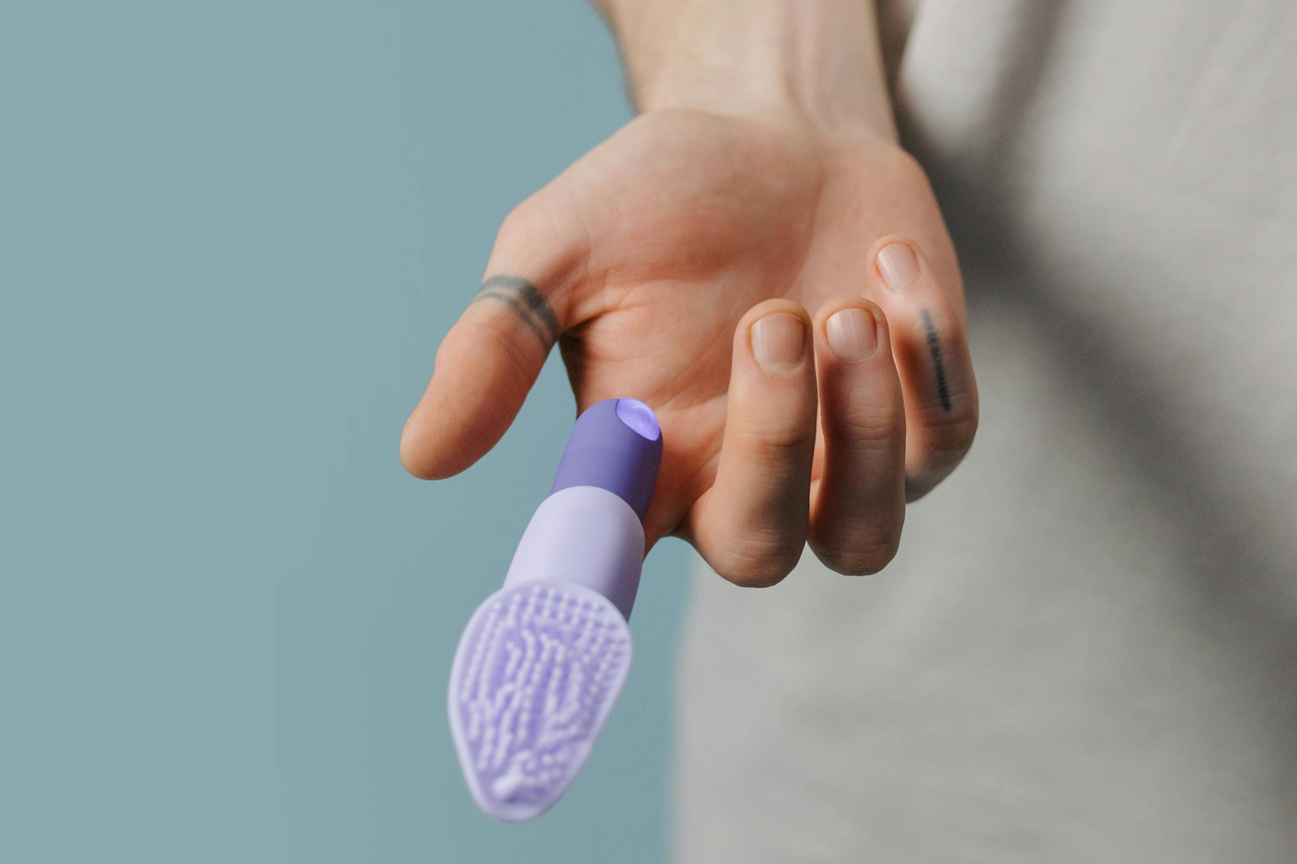 Person holding a small purple vibrator in hand
